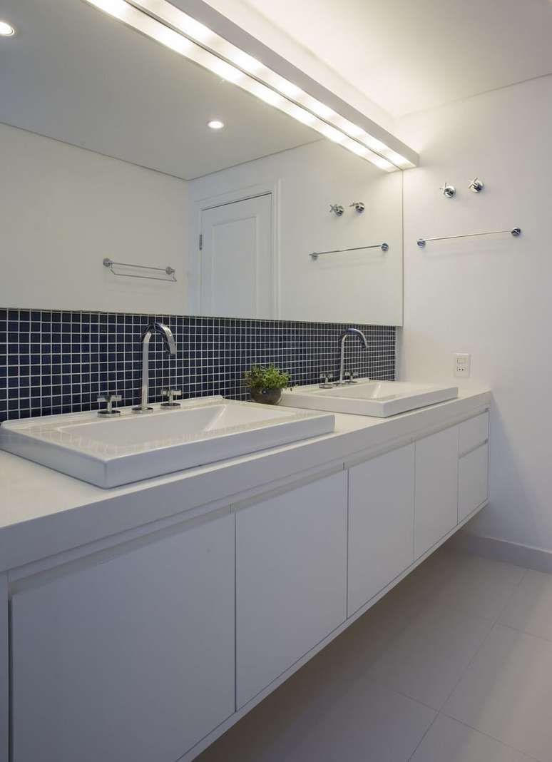 29. As pastilhas azul marinho se destacam no banheiro branco do projeto de Lima Orsolini Arquitetura