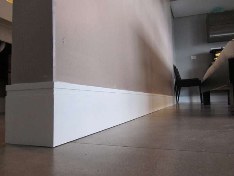 19- O rodap&eacute; de madeira alto deixa a sala com um estilo moderno. Fonte: Definitiva Decor