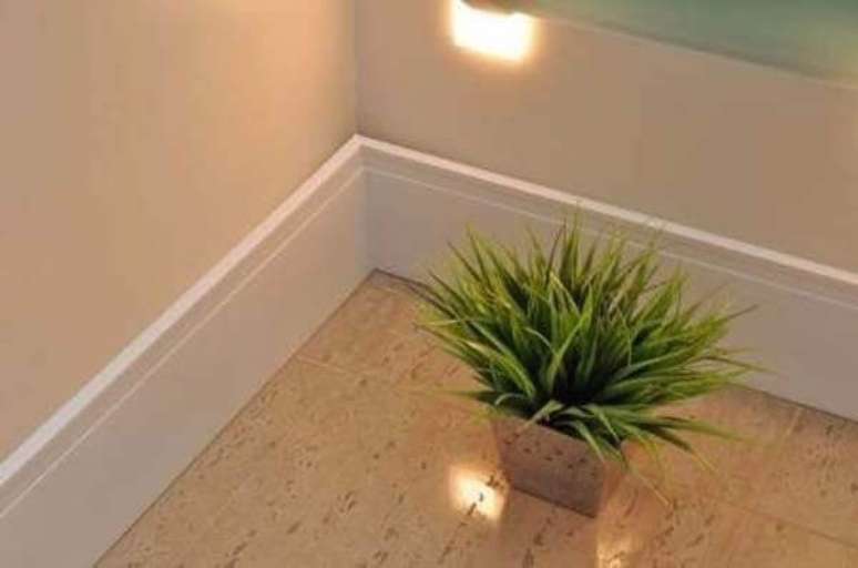 24- O rodap&eacute; de madeira branco pode complementar a decora&ccedil;&atilde;o de sala com piso frio. Fonte: Poliest Rodap&eacute;s e Acabamentos