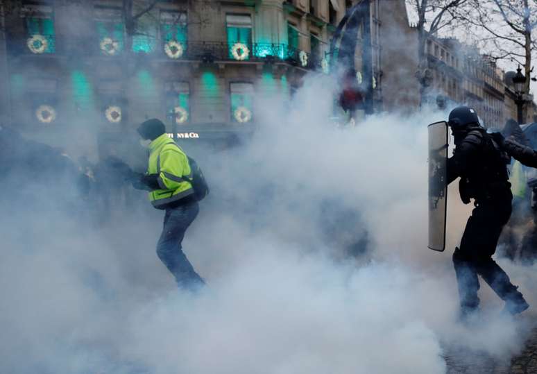 Manifestante corre em Paris enquanto polícia joga gás lacrimogênio para dispersar ato