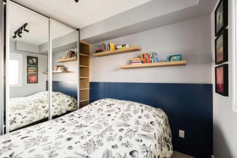 42. Arm&aacute;rio de quarto de solteiro com portas espelhadas e estante de madeira ao lado. Projeto de Zark Studio