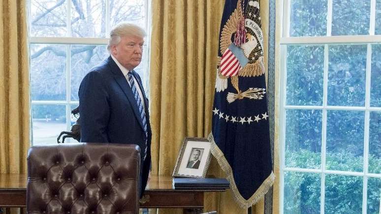 Donald Trump ao lado de um retrato de seu pai, na Casa Branca, em foto de 2017; presidente deu continuidade aos negócios de Fred