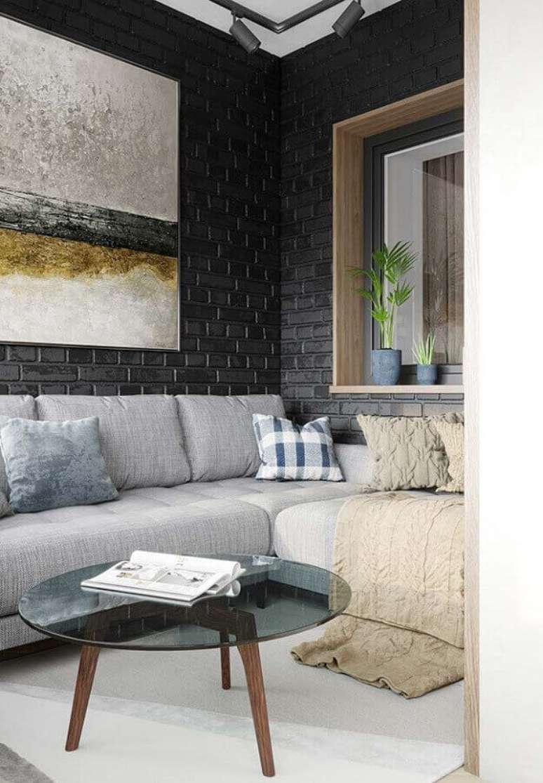 2. Decoração com estilo contemporâneo para sala de estar com parede de tijolinho pintada de preto, sofá cinza com manta bege – Foto: Whitesimgq