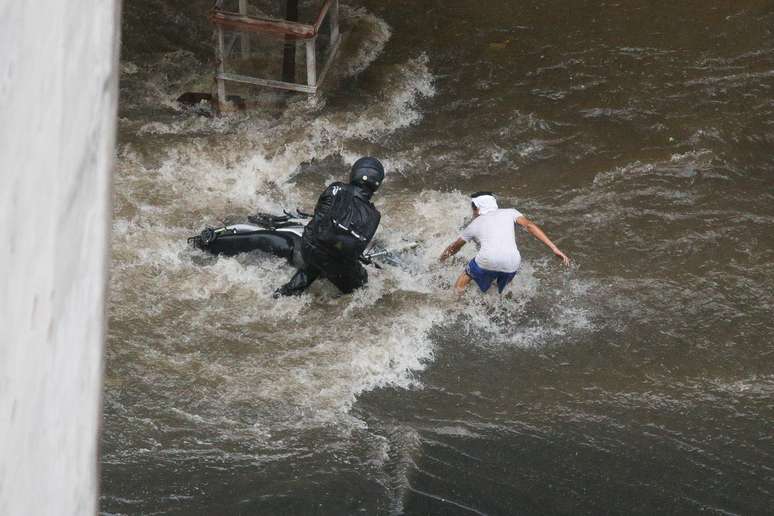 Pedestre ajuda motociclista arrastado pelas águas da chuva na Avenida Nove de Julho, no centro da capital paulista