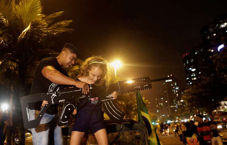 Apoiador de Bolsonaro ajuda menina a segurar arma de papelão, no Rio de Janeiro 28/10/2018 REUTERS/Ricardo Moraes