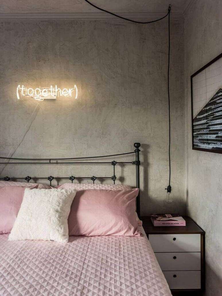38. Decoração para quarto feminino moderno com parede de cimento queimado, luminária sobre a cabeceira e cama de ferro – Foto: YouCanFind