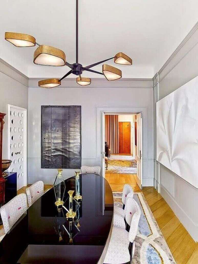 71- A sala de jantar tem lustre com detalhes em dourado e design arrojado. Fonte: Pinterest