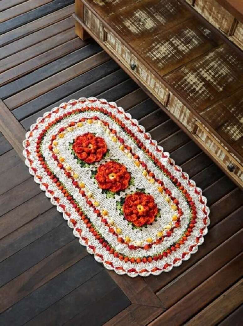 49. Modelo lindo e cheio de detalhes de tapete crochê oval com flor laranja – Foto: Croche Supreme