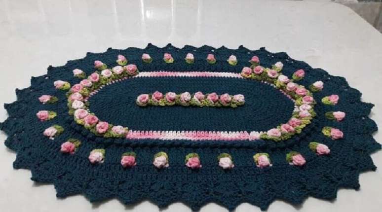 53. A flor de crochê para tapete azul marinho em tons de rosa bem claro ganhou muito destaque na peça artesanal – Foto: Nete