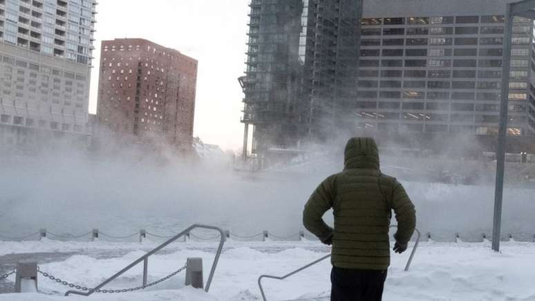 Imagem mostra homem de costas, em meio a prédios e ao chão coberto de neve em Chicago