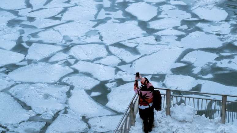 Imagem moistra pessoa fotografando lago congelado em Chicago, em meio à onde de frio que atinge os EUA