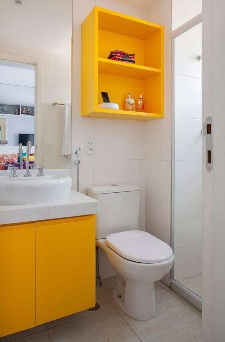 40. O nicho junto com o armário para banheiro pequeno pintados de amarelo trouxe mais alegria e luz para a decoração – Foto: Layde Linhares
