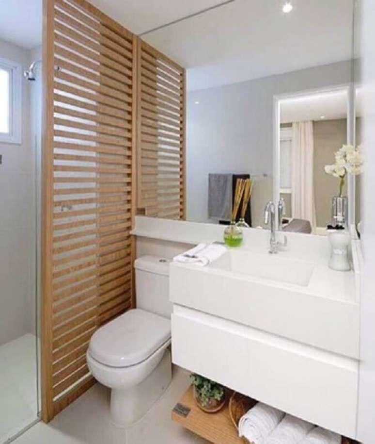 54. Decoração para banheiro pequeno planejado com divisória de madeira e parede espelhada – Foto: D+ Arquitetura