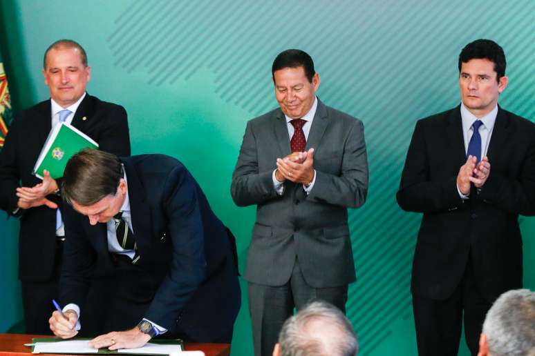 Presidente Jair Bolsonaro assina o decreto da posse de armas no Brasil sob os olhares do ministro da casa civil, Onyx Lorenzoni, do vice presidente Hamilton Mourão e do ministro da Justiça e Segurança Pública, Sergio Moro