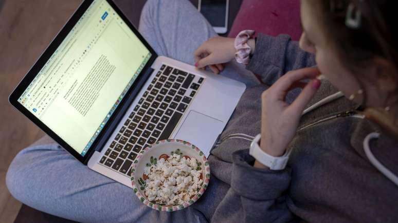 Louisa, 13, comendo pipocas enquanto faz lição de casa; adesão à dieta não foi unânime, mas lanchinhos ficaram mais saudáveis