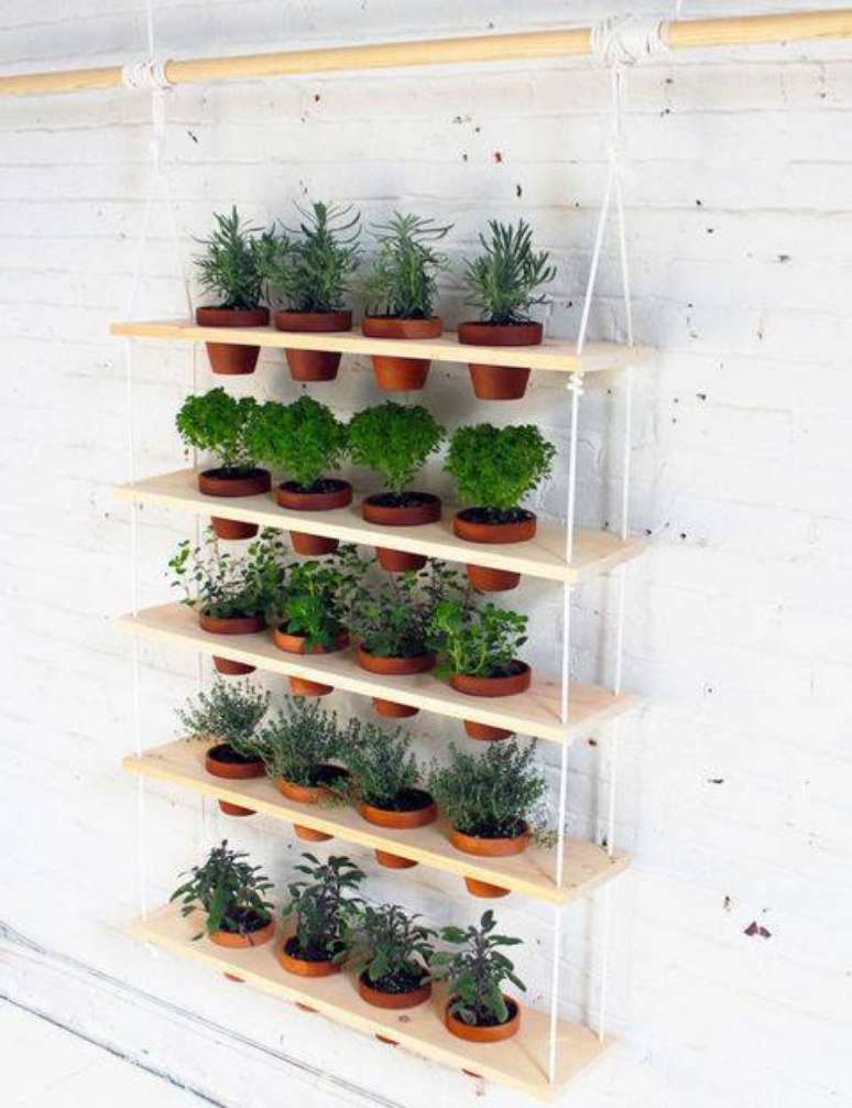 1. Esse tipo de horta vertical suspensa feita com madeira e vasos de barro, por exemplo, pode ser feita por você mesmo