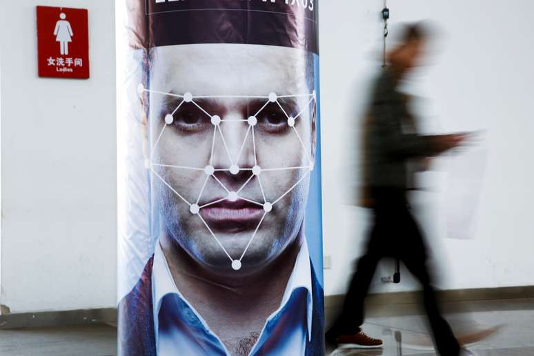 Homem passa por um poster que simula reconhecimento facial. 24/10/2018.   REUTERS/Thomas Peter