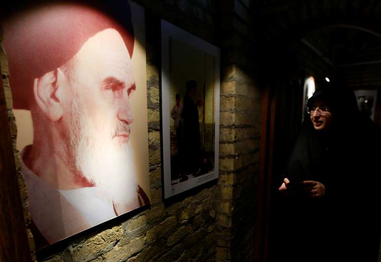 Mulher olha para imagem do aiatolá Ruhollah Khomeini, um dos líderes da revolução de 1979