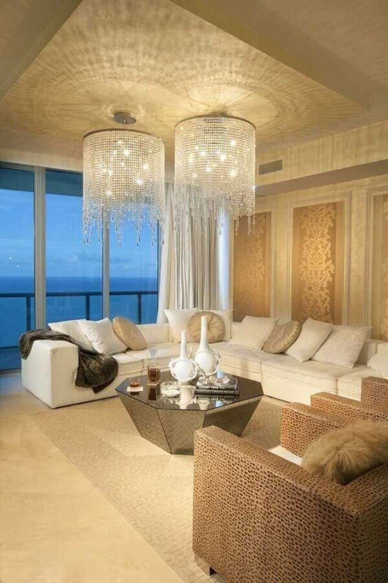 25. Decoração em tons neutros com dois lustres de cristal para sala de estar com amplo sofá branco – Foto:ArchiDom