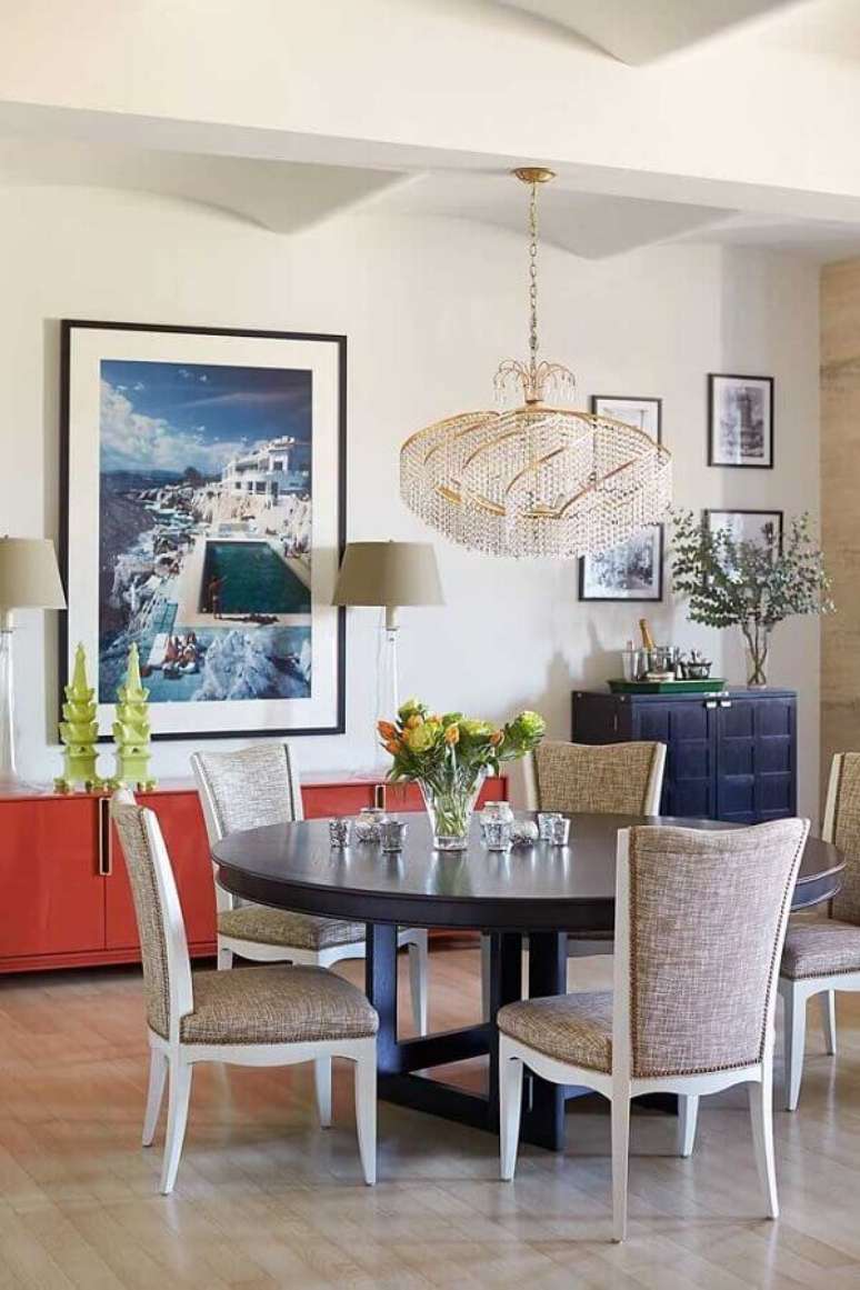 48. Lustre de cristal redondo para decoração de sala de jantar com mesa redonda e vários quadros na parede – Foto: HGTV