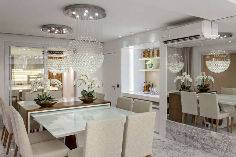 49. Decoração para sala de jantar pequena com parede espelhada e lustre de cristal redondo – Foto: Iara Kilaris