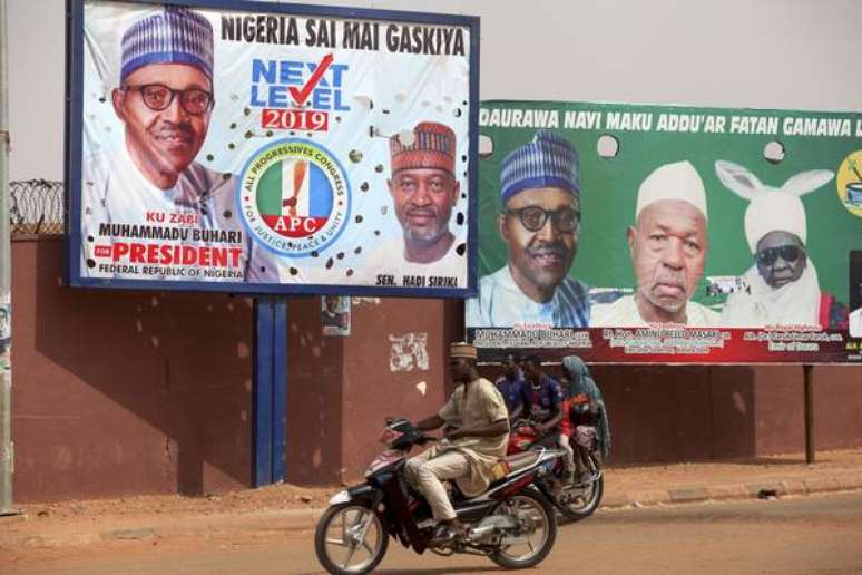 Cidadãos passam em frente a anúncios de campanha do presidente Buhari em Daura, na Nigéria