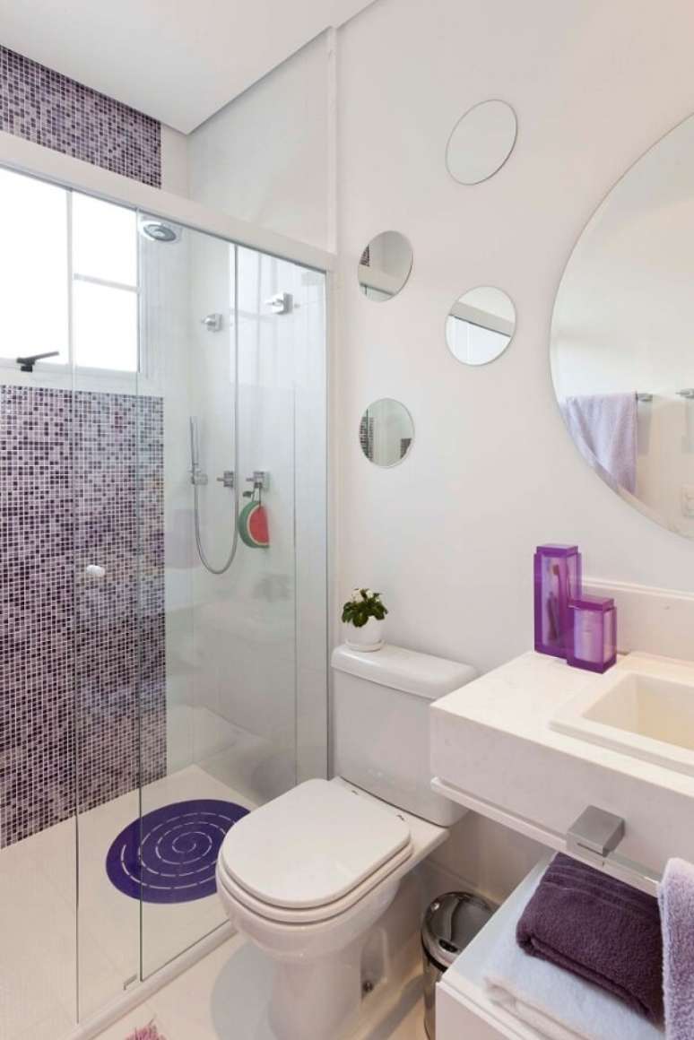 6- A decoração do banheiro pequeno tem pastilhas roxas no box e espelhos redondos na parede sobre a pia. Fonte: Viajando no apê