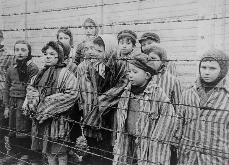 Crian&ccedil;as sobreviventes de Auschwitz, algumas delas identificadas pelo Museu do Holocausto, EUA: 'Tomasz Szwarz; Alicja Gruenbaum; Solomon Rozalin; Gita Sztrauss; Wiera Sadler; Marta Wiess; Boro Eksztein; Josef Rozenwaser; Rafael Szlezinger; Gabriel Nejman; Gugiel Appelbaum; Mark Berkowitz (um g&ecirc;meo); Pesa Balter; Rut Muszkies (depois Webber); Miriam Friedman; e as g&ecirc;meos Miriam Mozes e Eva Mozes, usando gorros tricotados