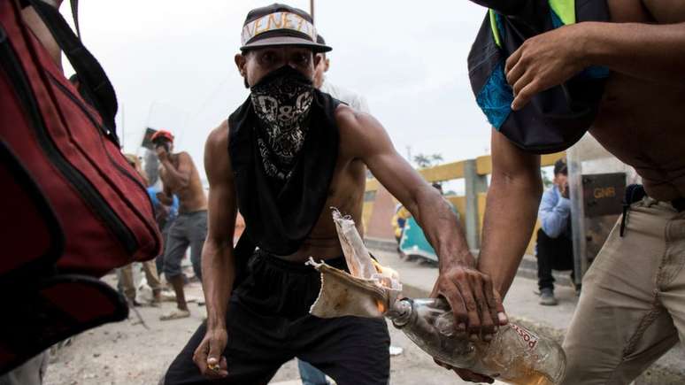 Homens encapuzados protestam durante tentativa de entrada de ajuda humanitária na Venezuela, no fim de semana