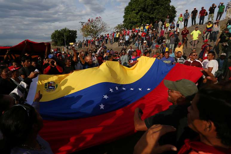 Manifestantes seguram bandeira da Venezuela durante protesto favorável ao governo na fronteira entre o país e o Brasil
24/02/2019 REUTERS/Bruno Kelly