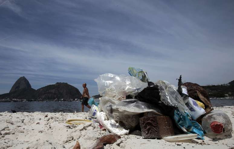 Homem caminha em meio a lixo na praia de Botafogo com o Pão de Açúcar ao fundo no Rio de Janeiro\
12/03/2014 REUTERS/Sergio Moraes
