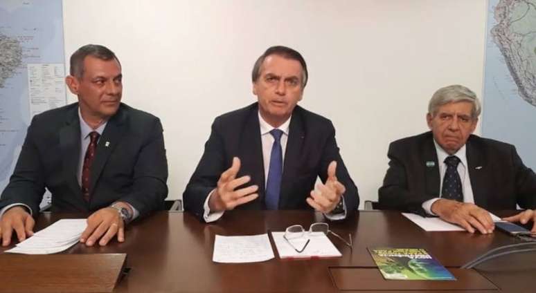 O general Otávio do Rêgo Barros (à direita), porta-voz do Planalto, o presidente Jair Bolsonaro e o general Augusto Heleno, ministro do GSI, em transmissão de vídeo no Facebook 