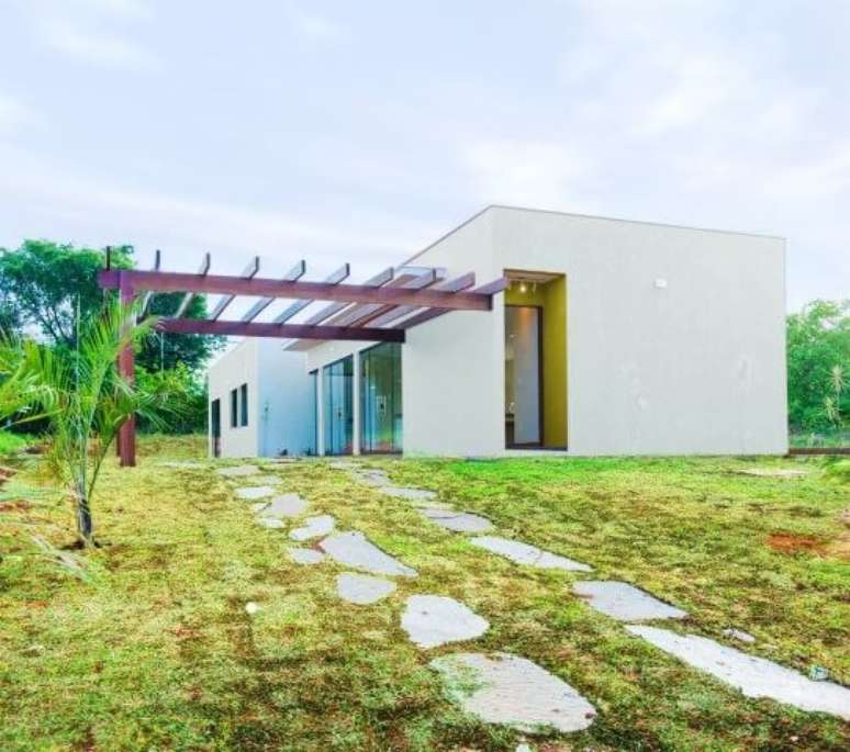 81. Fachada de casa moderna com pergolado de madeira e caminho de pedras &ndash; Foto: Mateus Castilho