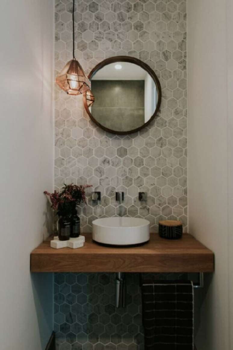 35. Cuba pequena para lavabo simples decorado com bancada de madeira e espelho redondo – Foto: The Spruce