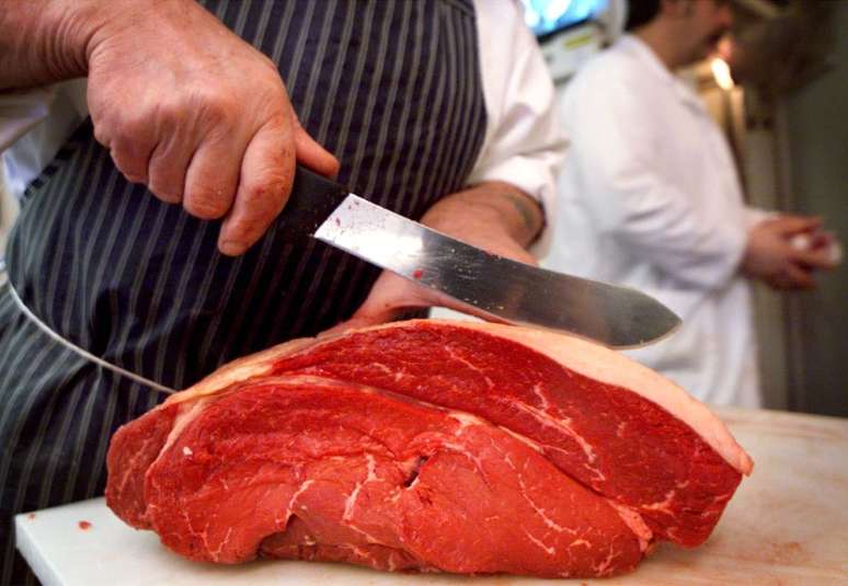 Homem corta peça de carne bovina
