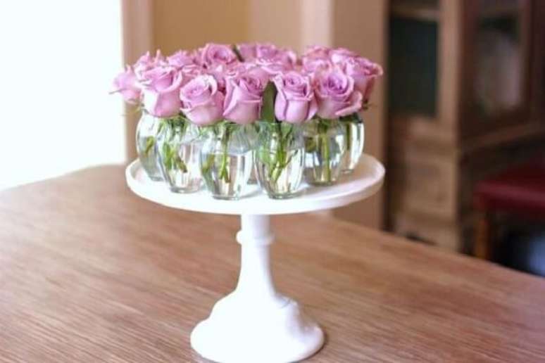 24- Na decoração dia das mães, o arranjo central da mesa é formado por vários vasinhos transparentes com rosas lilás. Fonte: Ambientes de Charme