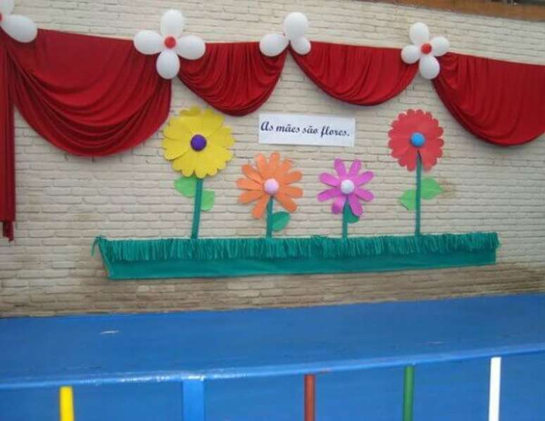 50- A decoração dia das mães na escola tem canteiro com flores de papel e cortina em TNT colados na parede. Fonte: Como Fazer em Casa