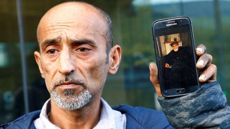 Omar Nabi mostra um celular com a foto de seu pai, Daoud, primeira vítima do ataque a ser identificada