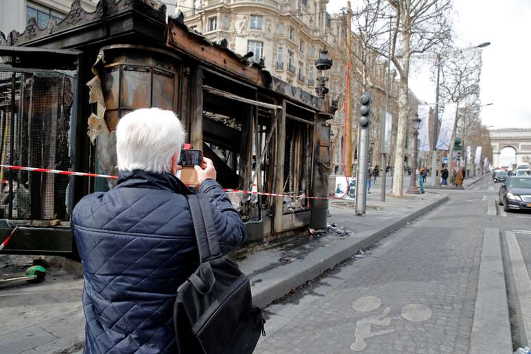 Homem tira foto de banca de jornal incendiada após protesto dos "coletes amarelos" na avenida Champs Élysées em Paris, na França
18/03/2019
REUTERS/Philippe Wojazer