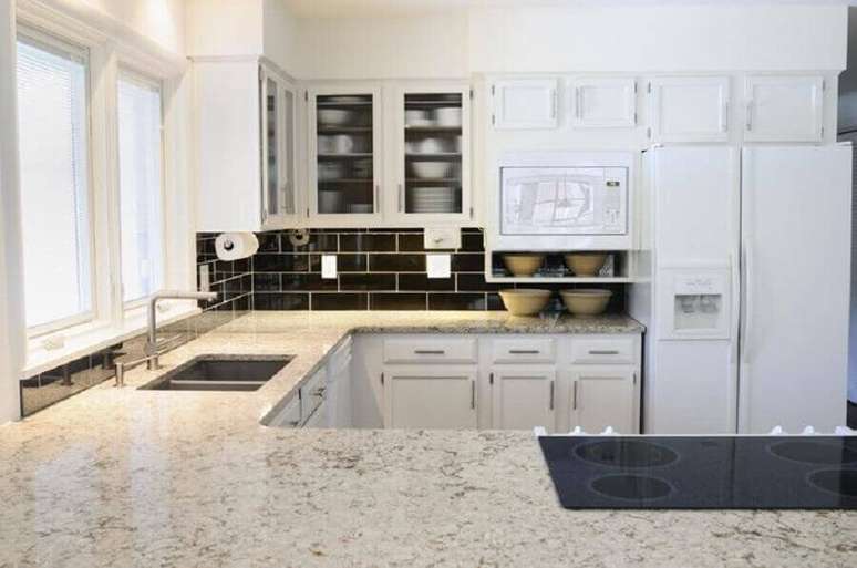 63. Granito branco Polar para decoração de cozinha com armários planejados e azulejo preto – Foto: Istock