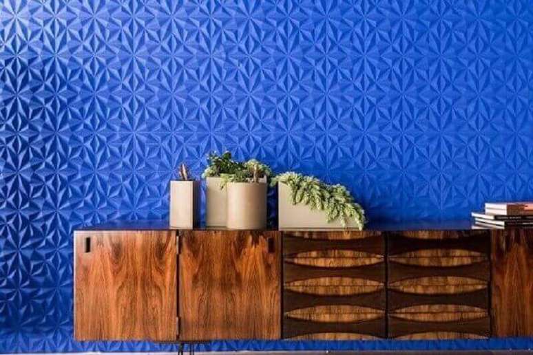 52. Parede com revestimento 3D em tom de azul royal com armário de madeira e plantas – Foto: Guilherme Torres