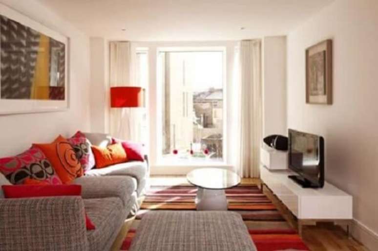 12- A decoração de sala simples e barata tem almofadas, tapete e abajur em tons de vermelho. Fonte: Mulher Portuguesa