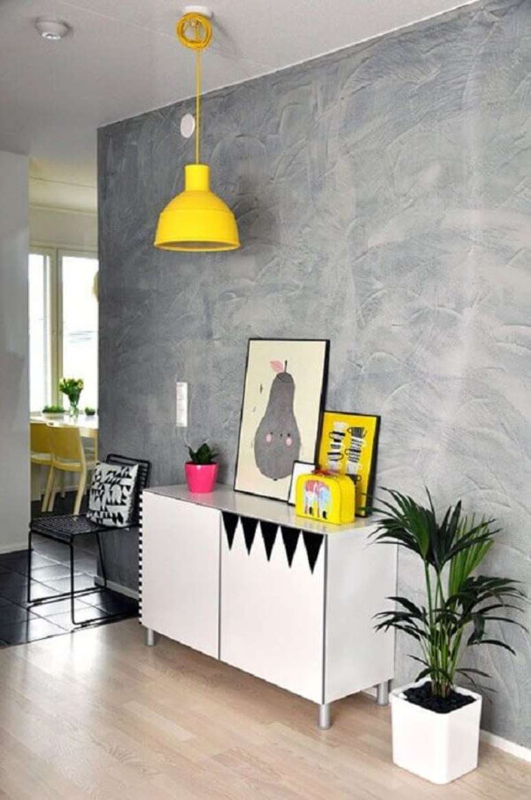 19- Na decoração de sala simples e barata, a parede de cimento aparente contrasta com os acessórios amarelos. Fonte: Dcore Você