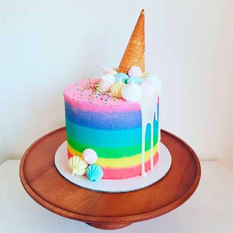 68.. Os bolos decorados simples também pode ser bem divertidos como esse de arco-íris e casquinha de sorvete no topo – Foto: Testa pra Mim