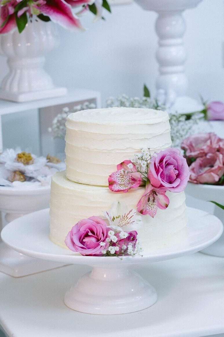 78. Decoração de bolo de casamento com flores cor de rosa e cobertura de chantilly branco – Foto: Julia Guedes