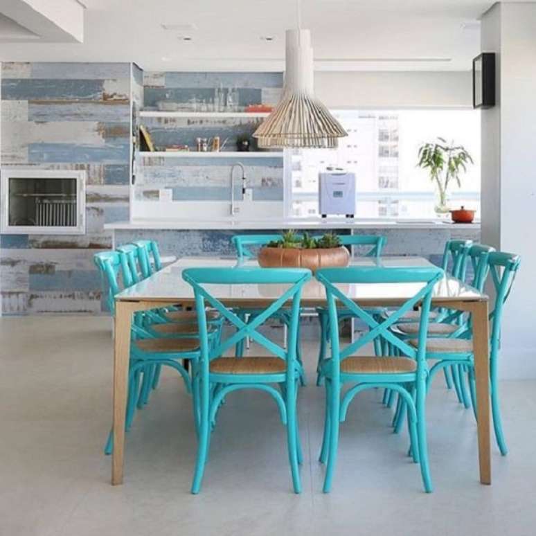 53 – As cadeiras no tom azul turquesa transmitem requinte para essa sala de jantar integrada com a churrasqueira. Projeto SP Estúdio