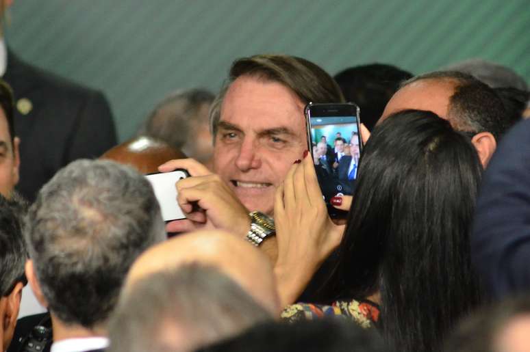 O presidente Jair Bolsonaro participa ao lado do ministro da Economia, Paulo Guedes, de cerimônia de sanção da lei do cadastro positivo, no Palácio do Planalto, em Brasília, nesta segunda-feira (8).