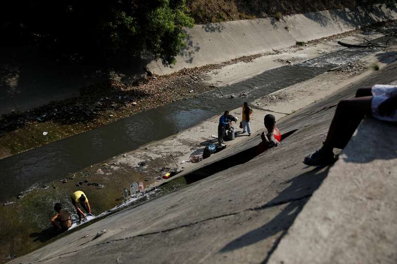Pessoas pegam &aacute;gua em canal do rio Guaire, que recebe a maior parte do esgoto de Caracas
01/04/2019
REUTERS/Carlos Garcia Rawlins