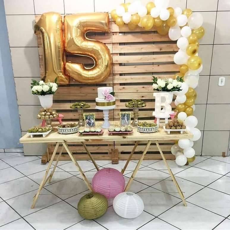 10. Decoração simples para festa de 15 anos com painel de pallets e balões dourados – Foto: Le’ Art Decor