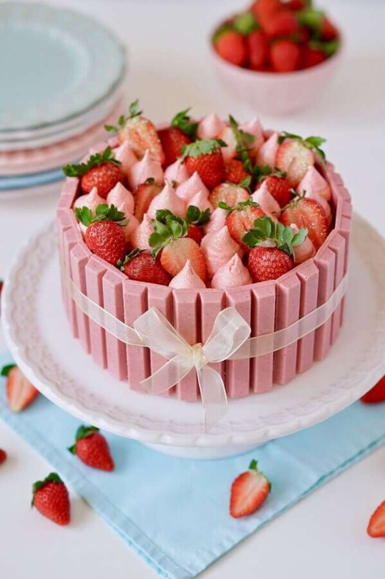 8. Lindo bolo de festa de aniversário decorado com chocolate rosa, muitos morangos e suspiros no topo – Foto: Flamboesa